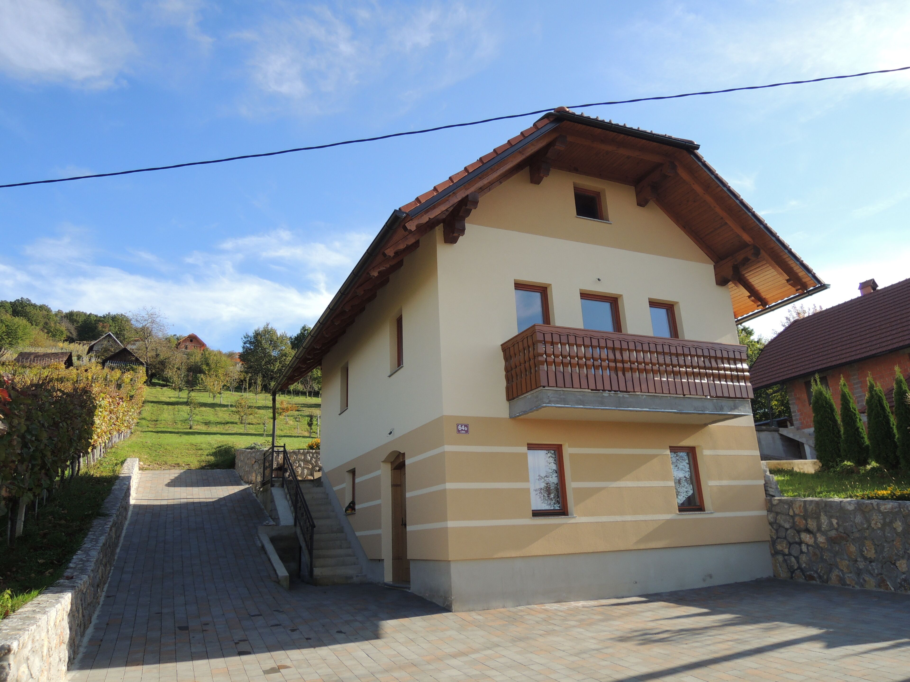 Una casa a due piani con un balcone, un muro in pietra e un vialetto lastricato.