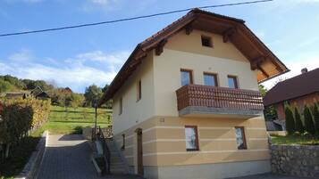Una casa a due piani con un balcone, un muro in pietra e un vialetto lastricato.