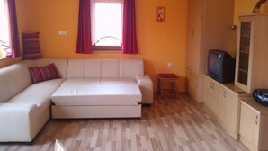 A small, bright living room with a sofa, a television, and a cabinet.