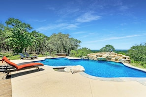 Une piscine au design incurvé, entourée de chaises longues et d’une terrasse.