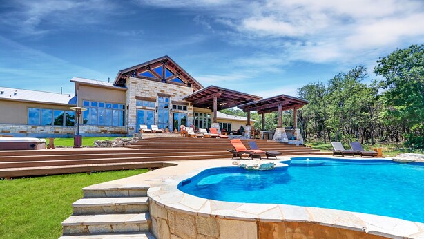 Una casa moderna con piscina, zona de estar al aire libre y una escalera de piedra que conduce a la entrada.