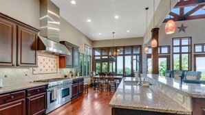 Una cocina amplia con una isla grande, armarios de madera y vistas a través de amplias ventanas.