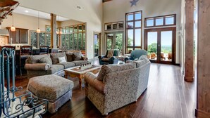 Un salón comedor amplio con techo alto, ventanas grandes y una zona de estar acogedora.