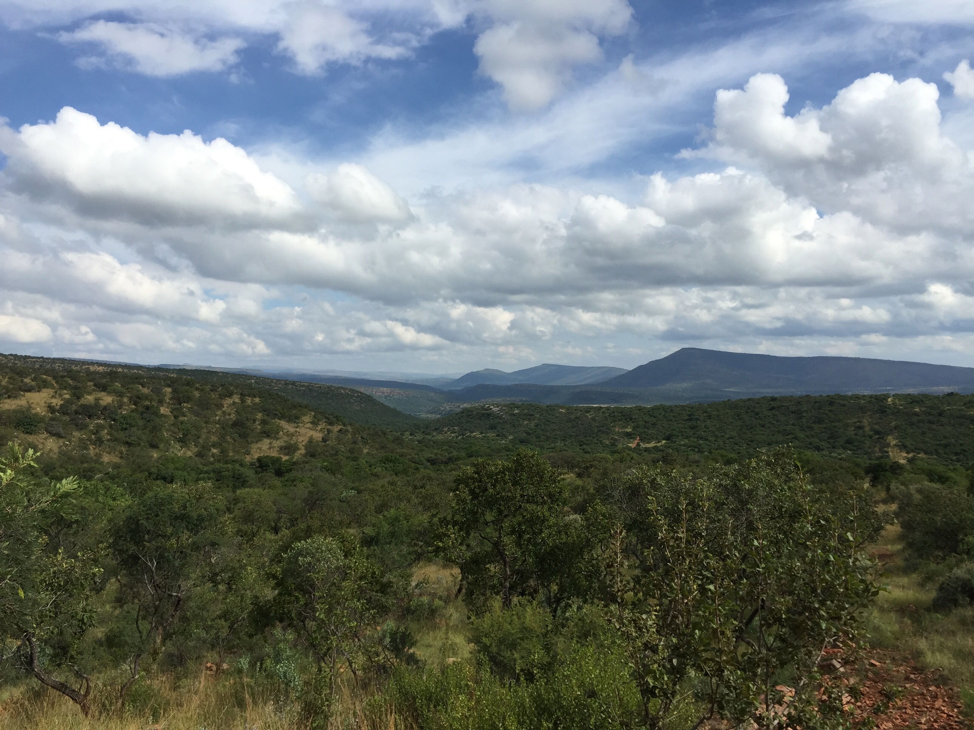 Un paisaje natural con un valle, montañas y un cielo nublado.