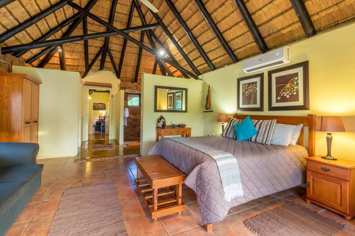 A spacious bedroom with a large bed, wooden bench, and a nightstand.