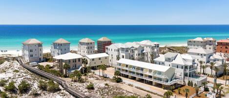 A coastal hotel with multiple buildings, a beach access walkway, and a view of the ocean.