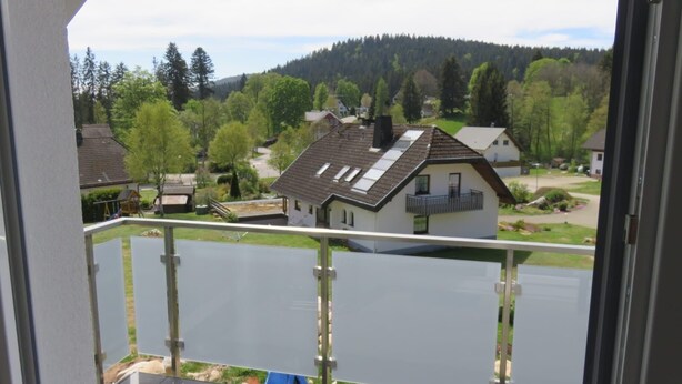 Una zona residencial con casas, un lago y una colina boscosa al fondo.