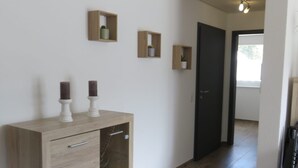 Un pasillo con un armario de madera, una puerta negra y un sofá de cuero negro.