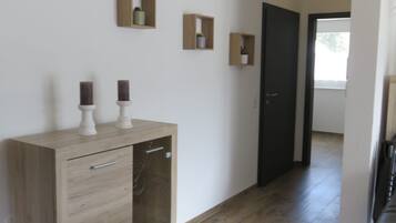 Ein Flur mit einem Holzkasten, einer schwarzen Tür und einem schwarzen Ledersofa.