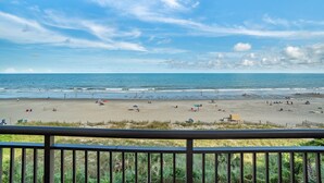 A beach with people, umbrellas, and a fence. - Gorgeous View Oceanfront Condo w/ Hug Sundeck Balcony (Myrtle Beach)