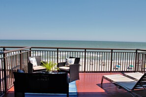 A balcony with wicker furniture, a potted plant, and a view of the beach. - Gorgeous View Oceanfront Condo w/ Hug Sundeck Balcony (Myrtle Beach)