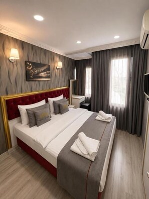 A hotel room with a large bed, a bedside table, a mirror, and a TV. - Rhythm Hotel (Istanbul)