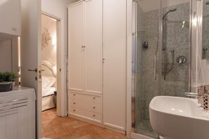 Un baño con ducha, lavamanos y armario.