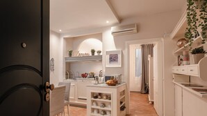 Une cuisine compacte avec des meubles blancs, un petit îlot doté d’étagères et un four à micro-ondes.