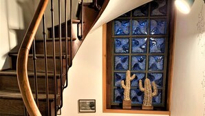 A wooden spiral staircase with a glass window featuring a cactus decoration.