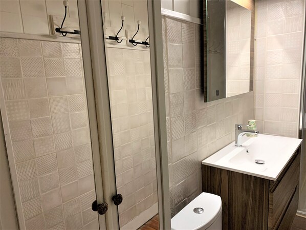 A modern bathroom with a glass shower enclosure, a white toilet, and a sink with a wooden vanity.