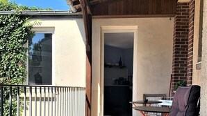 A balcony with a tiled floor, a metal railing, a table, and two chairs.