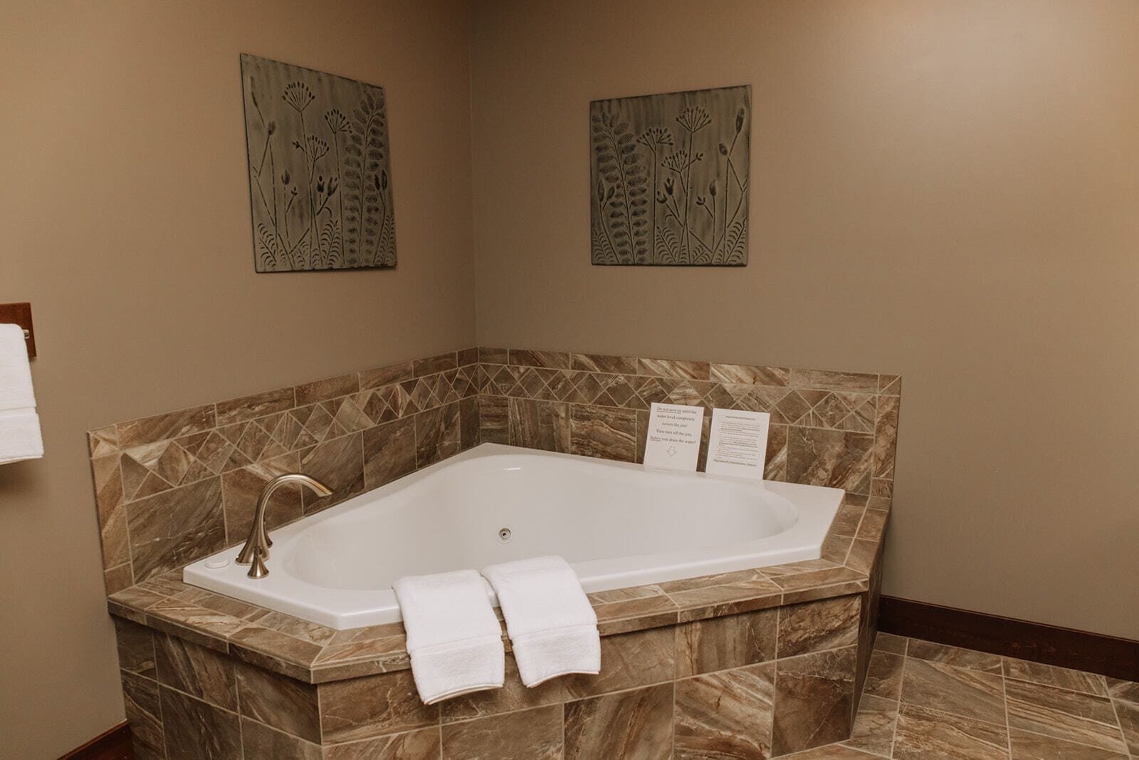 A modern bathroom with a freestanding bathtub, marble tiles, and two wall-mounted artwork pieces.
