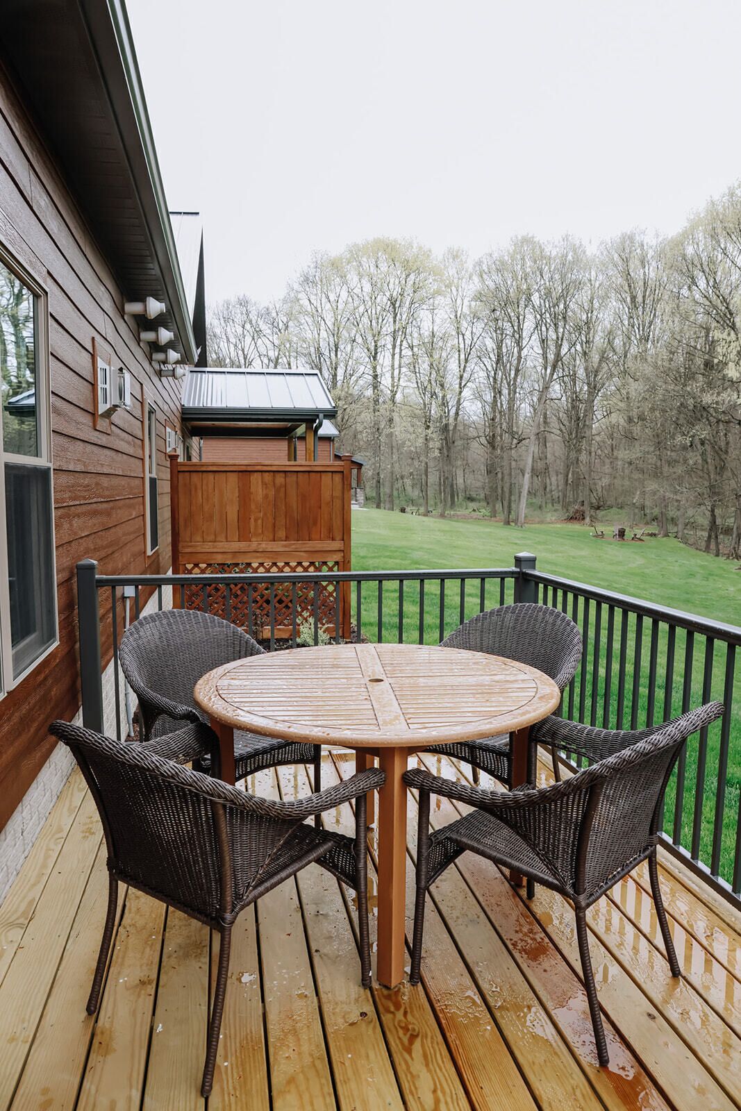 A wooden deck with a round table and four wicker chairs.