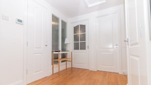 A room with white doors, a wooden floor, a small table with a lamp, and a window with frosted glass. - Seaview Cottage (Dundee)