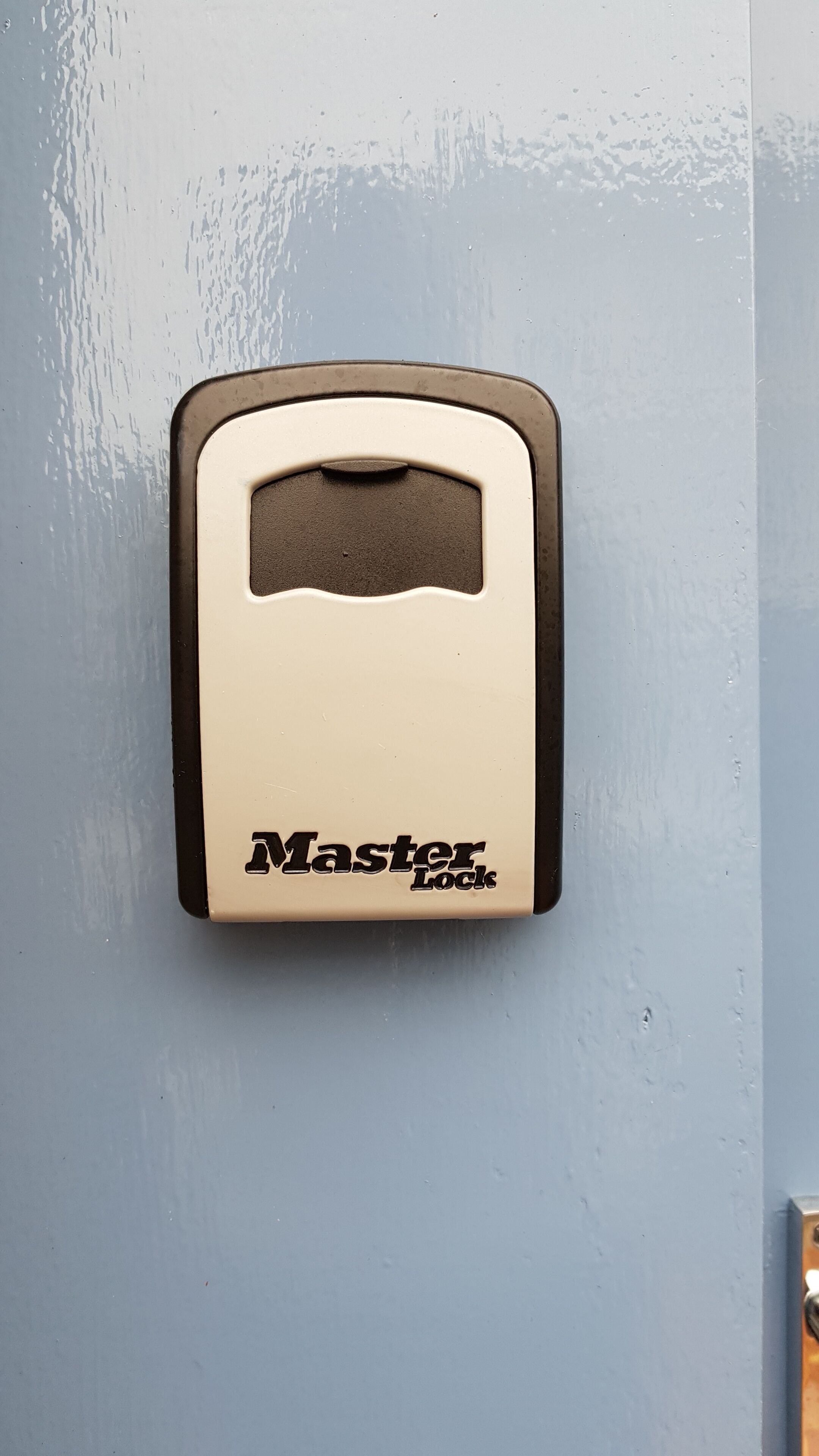 A Master Lock padlock on a light blue door.
