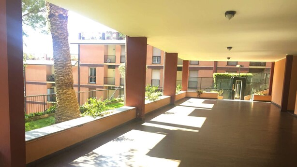A covered corridor with tiled flooring, large windows, and a view of a building with balconies. - Casa di Giò (Rapallo)
