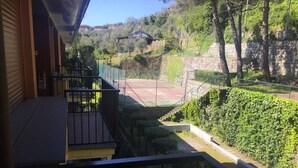 A balcony with a view of a tennis court and surrounding greenery. - Casa di Giò (Rapallo)