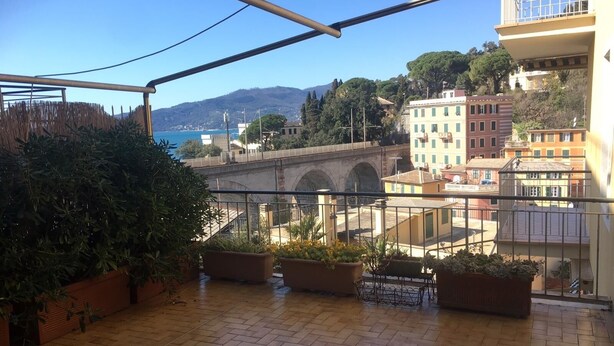 Ein Balkon mit Fliesenboden, Blumentöpfen und Blick auf eine Brücke sowie Gebäude.