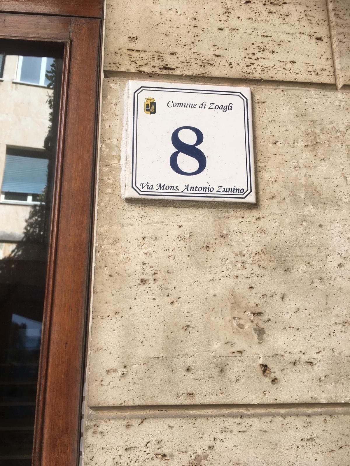 Une plaque indiquant le numéro de l’immeuble, portant le chiffre 8, et précisant l’adresse.