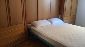 Ein Einzelbett mit weißer Bettwäsche in einem Zimmer mit Holzwandverkleidung und einer blauen Bank.