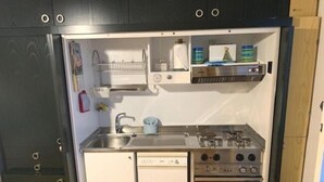 Eine kleine Küche mit Spüle, Geschirrspüler, Herd und Stauraumschränken.