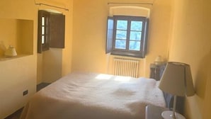 Ein Schlafzimmer mit einem Bett, einem Fenster, einer Heizung und einer Lampe.
