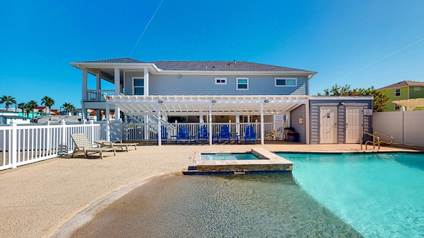 Une maison à deux étages avec une piscine, un patio couvert avec des chaises et une terrasse clôturée.