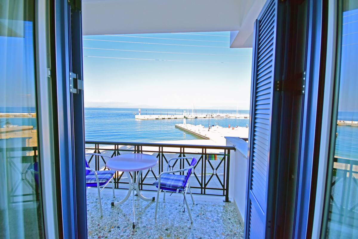 Un balcón con vista al mar, una mesa y dos sillas.