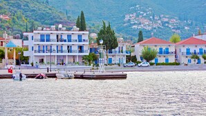 Un bâtiment situé au bord de l’eau, doté de balcons, d’un quai et offrant une vue sur une ville perchée sur une colline.