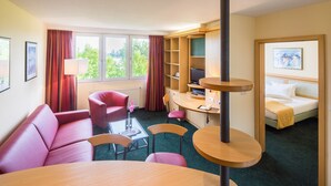 Una habitación de hotel con sofá, escritorio, silla, cama y televisor.