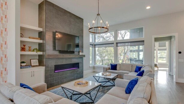 Una sala moderna con chimenea, ventanas amplias y un conjunto de sofás.