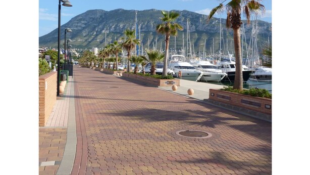 A marina with boats docked, a paved walkway, palm trees, and a mountain in the background. - SPACIOUS APARTMENT NEAR THE BEACH WIFI, A/C  (Dénia)