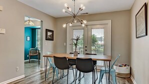 Un espace repas avec une table en bois, des chaises noires et un lustre moderne.