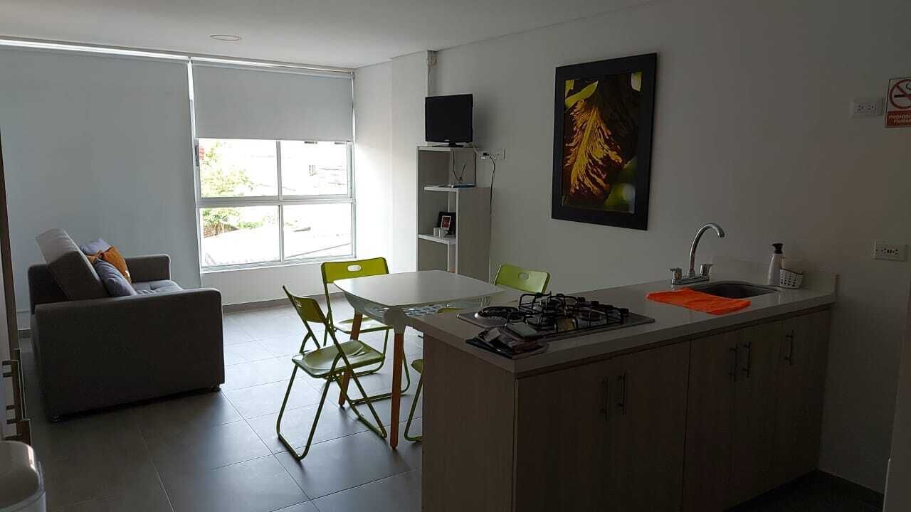 A modern kitchen with a dining area, a sofa, and a TV.