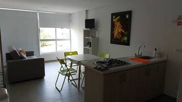 A modern kitchen with a dining area, a sofa, and a TV.