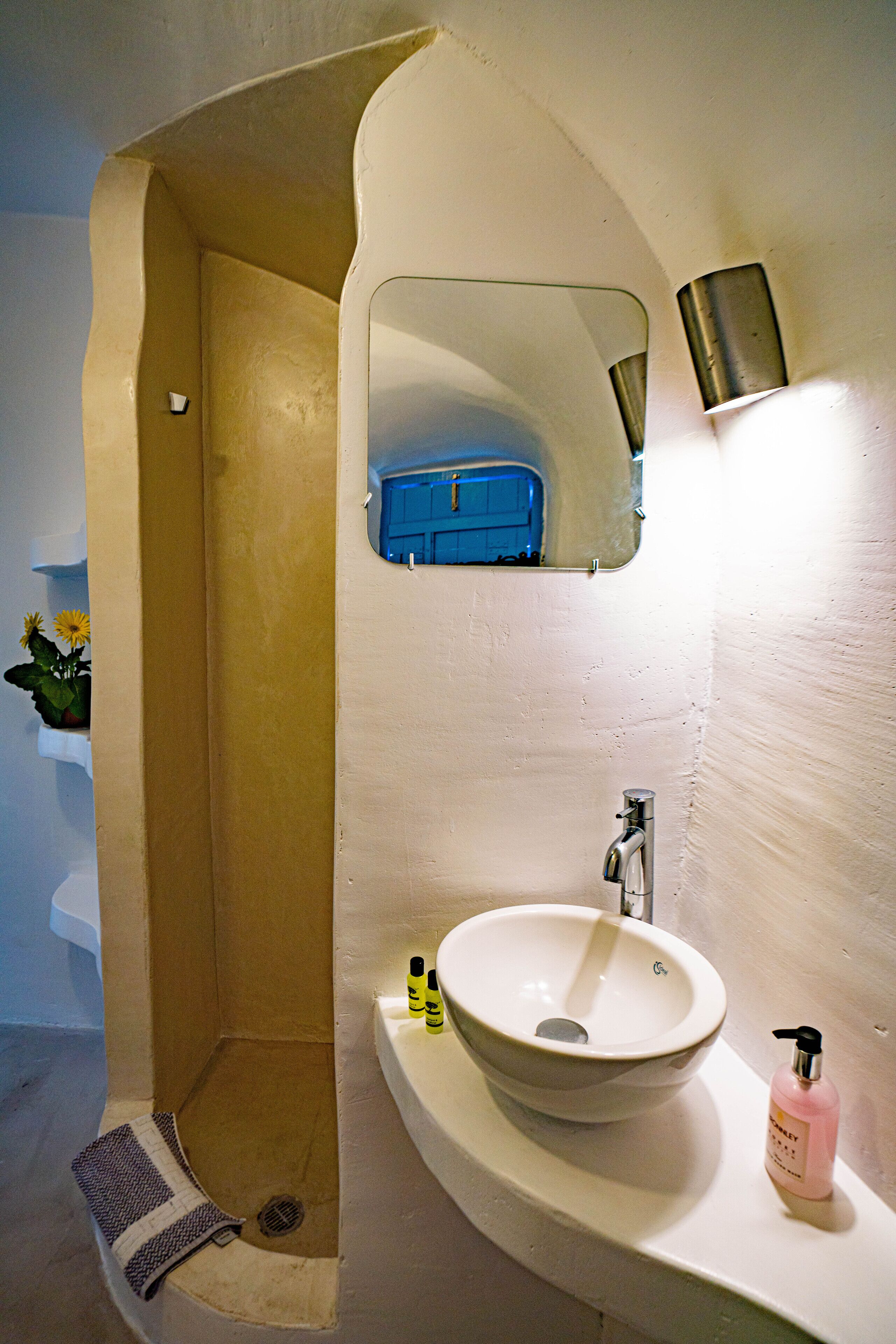 A bathroom with a white sink, a mirror, and a blue cabinet.