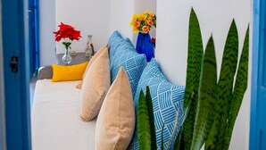 A room with a bed, pillows, a vase with flowers, and a plant.