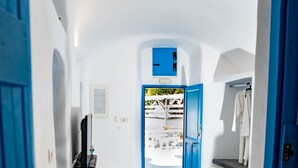 A room with a dining table set for two, a blue door, and a view of the outside.