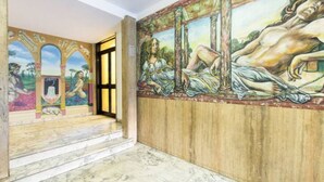 A hallway with a mural depicting a classical scene, marble flooring, and a wooden panel wall. - B&B di Paolo S. (Rome)