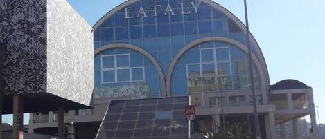 A modern building with a curved glass facade and the word 'EATALY' prominently displayed.