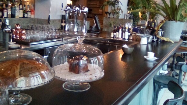 A bar area with a long counter, shelves with bottles, and a chandelier. - B&B di Paolo S. (Rome)
