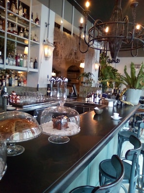 A bar area with a long counter, shelves with bottles, and a chandelier. - B&B di Paolo S. (Rome)