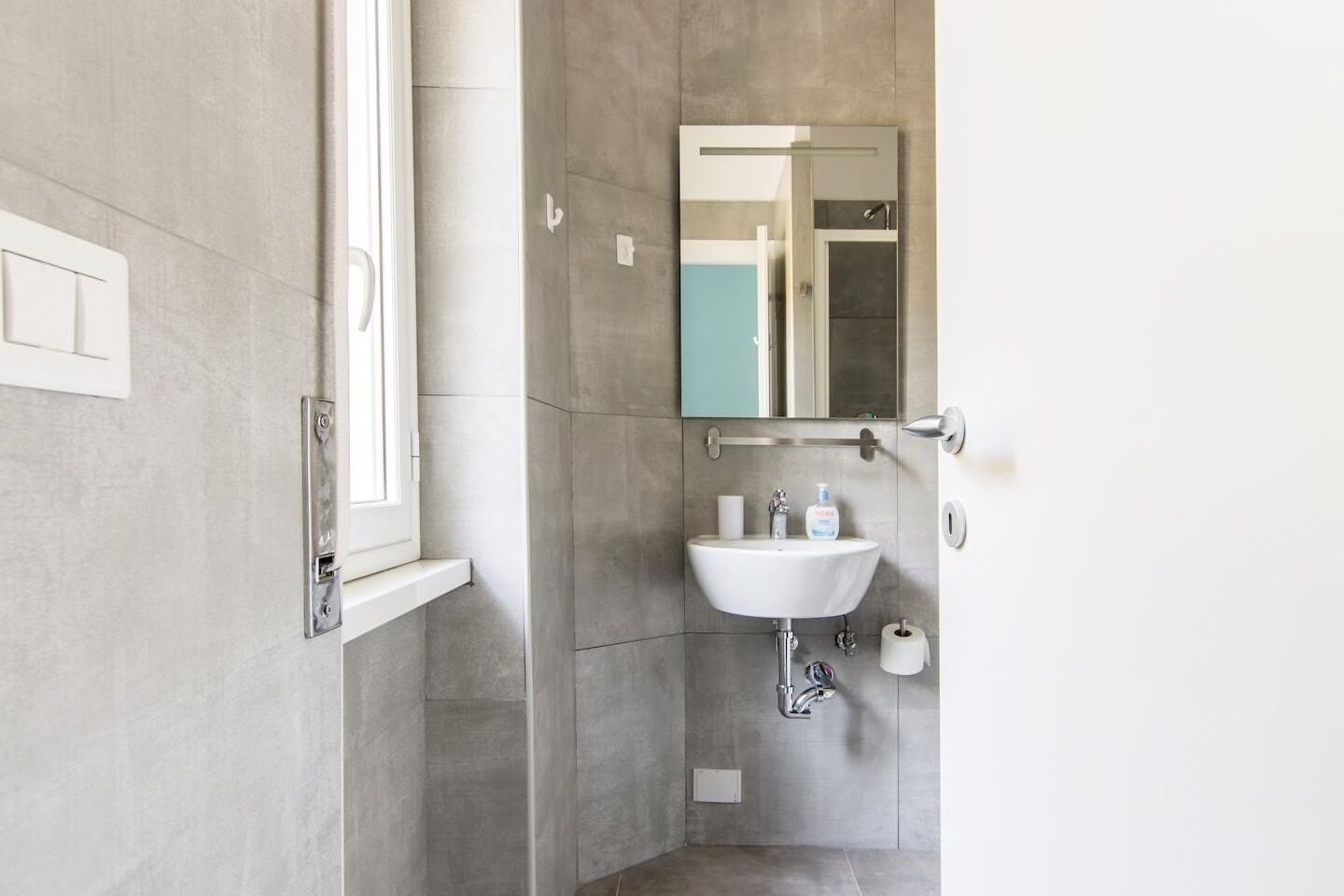 Ein Badezimmer mit einem weißen Waschbecken, einem Spiegel und einer Dusche.