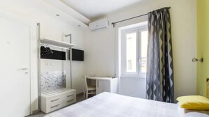 A bedroom with a bed, a desk, a wardrobe, and a window with curtains. - B&B di Paolo S. (Rome)